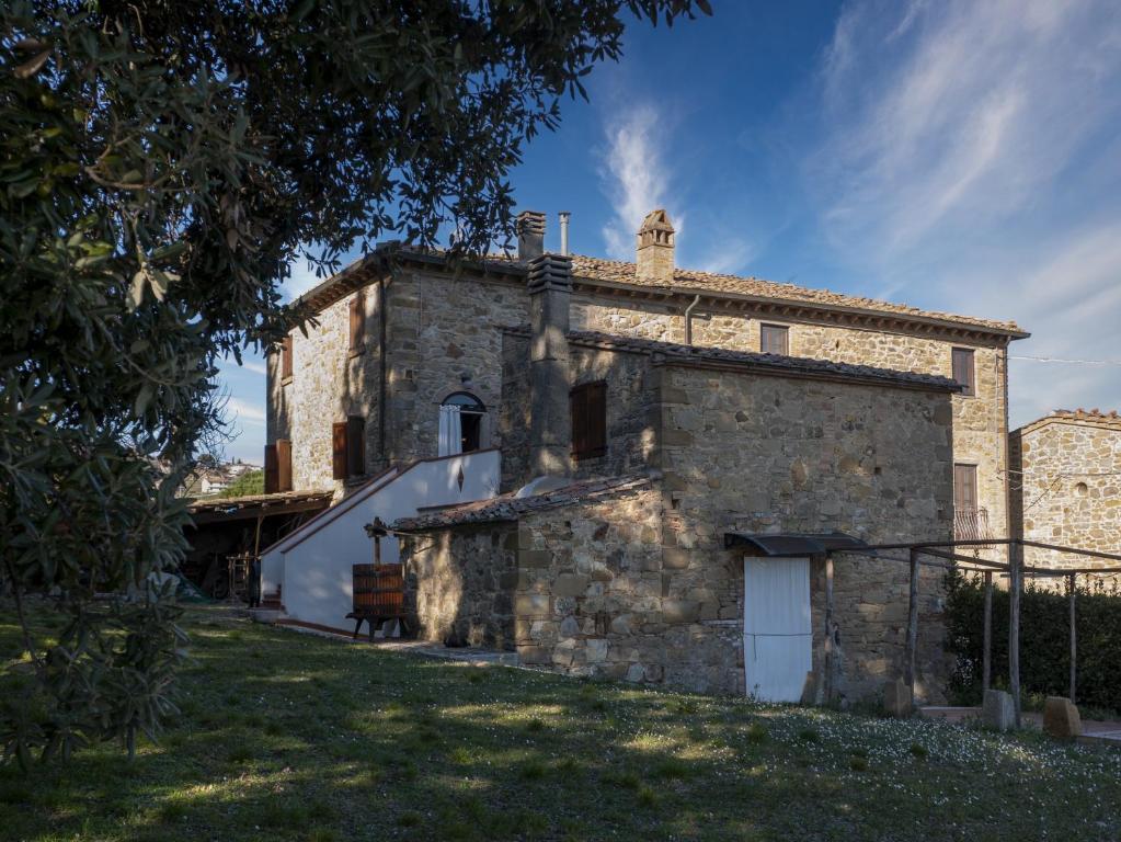 un vecchio edificio in pietra con una porta bianca in un cortile di CASALE PANORAMICO Villa Vinombrosa a Chianni