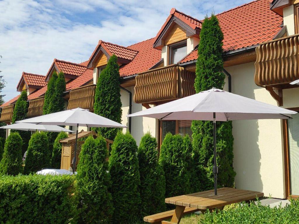 two white umbrellas and a table in front of a building at Villa Lavenda in Grzybowo