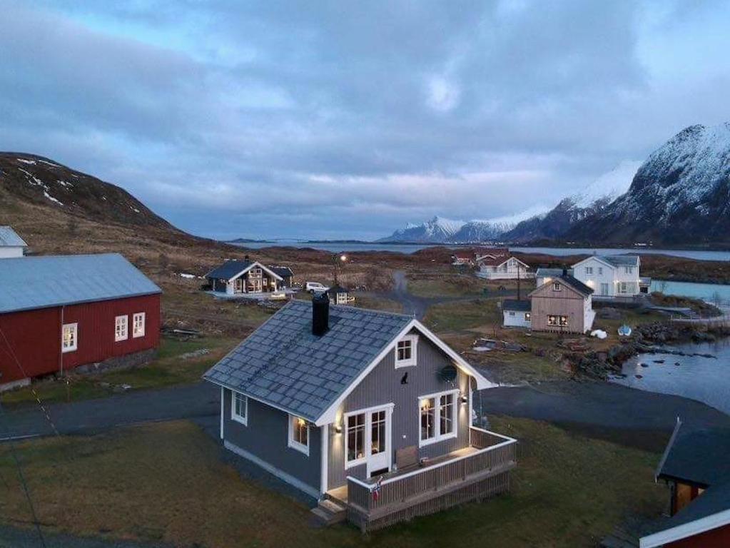 a small house in a field with mountains in the background at Fredvang Panorama Lofoten in Fredvang