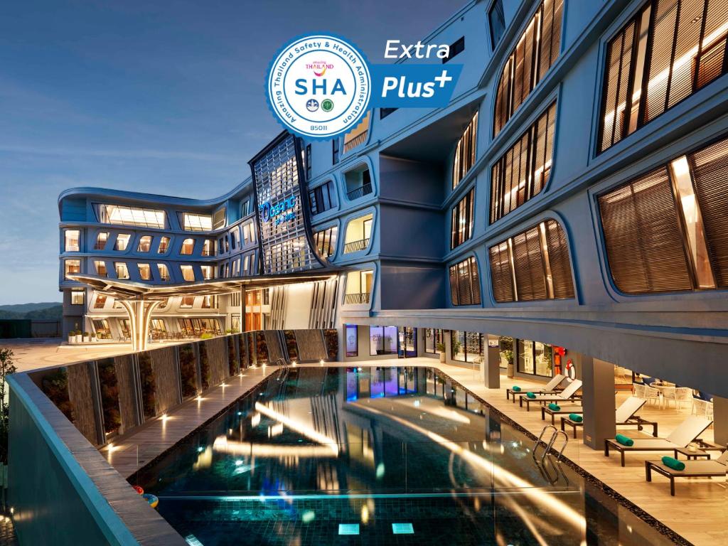 a hotel with a swimming pool in front of a building at The Oceanic Sportel Phuket - SHA Extra Plus in Phuket