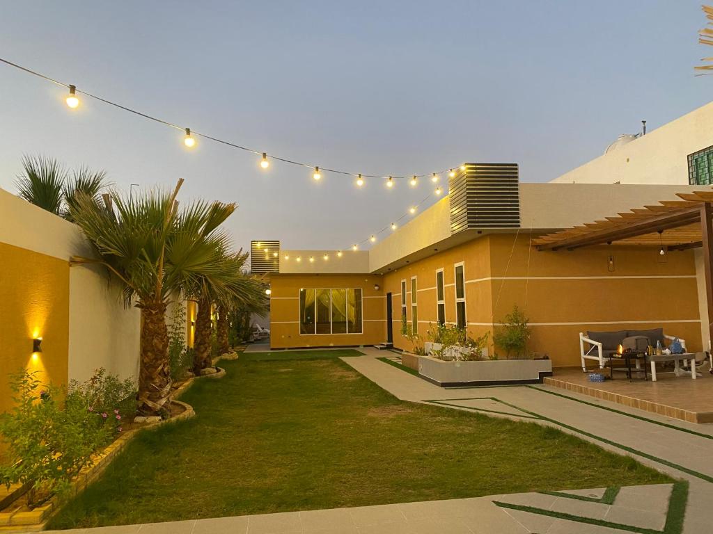 una casa con un patio con césped y luces en شالية لورينزو, en Buraidah