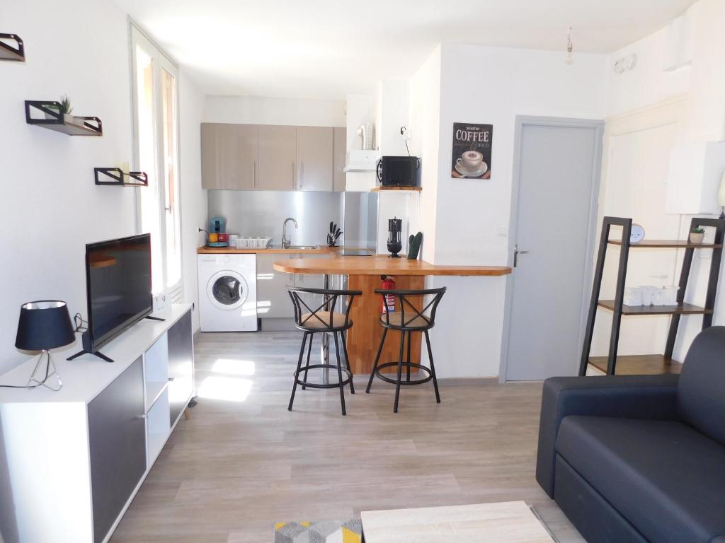 une cuisine et un salon avec une table dans une pièce dans l'établissement Appartement tout équipé à 15 min des plages, à Béziers