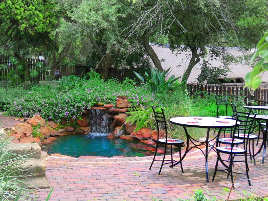 a table and chairs and a pond with a fountain at Pine Valley in Lanseria