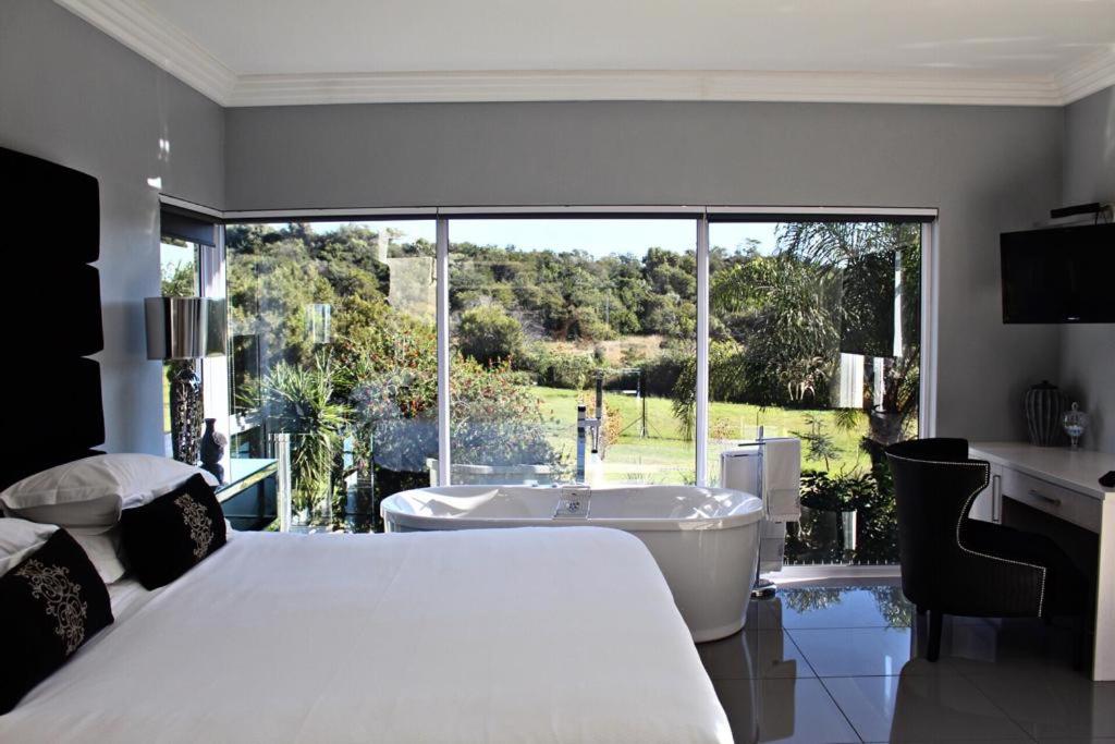 a bedroom with a bed and a tub and a window at North Haven Country Estate in Honeydew