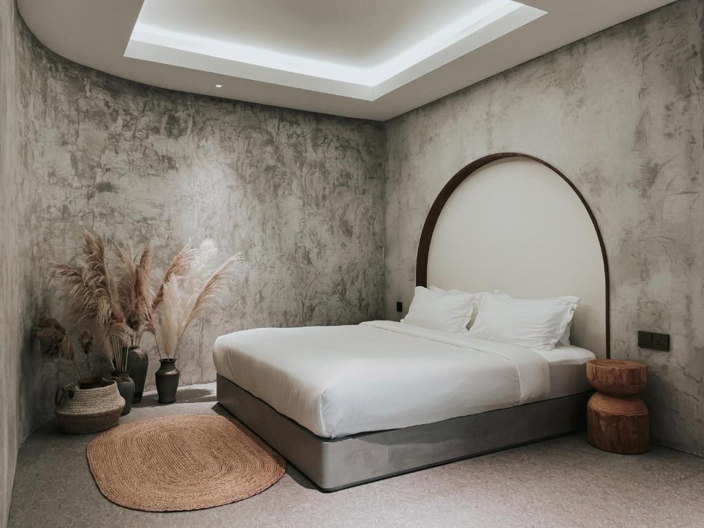 The Cara Boutique Hotel في كوتا كينابالو: غرفة نوم مع سرير أبيض مع اللوح الأمامي المقوس