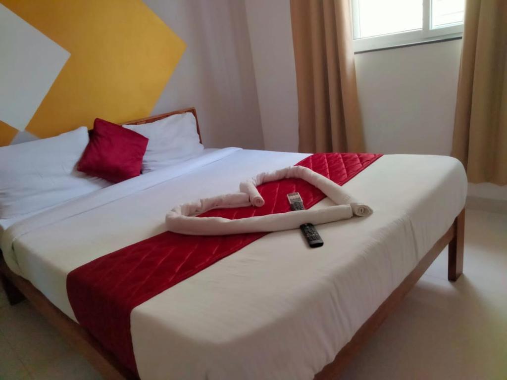 a white bed with a remote control on top of it at SERENE INTERNATIONAL in Bangalore
