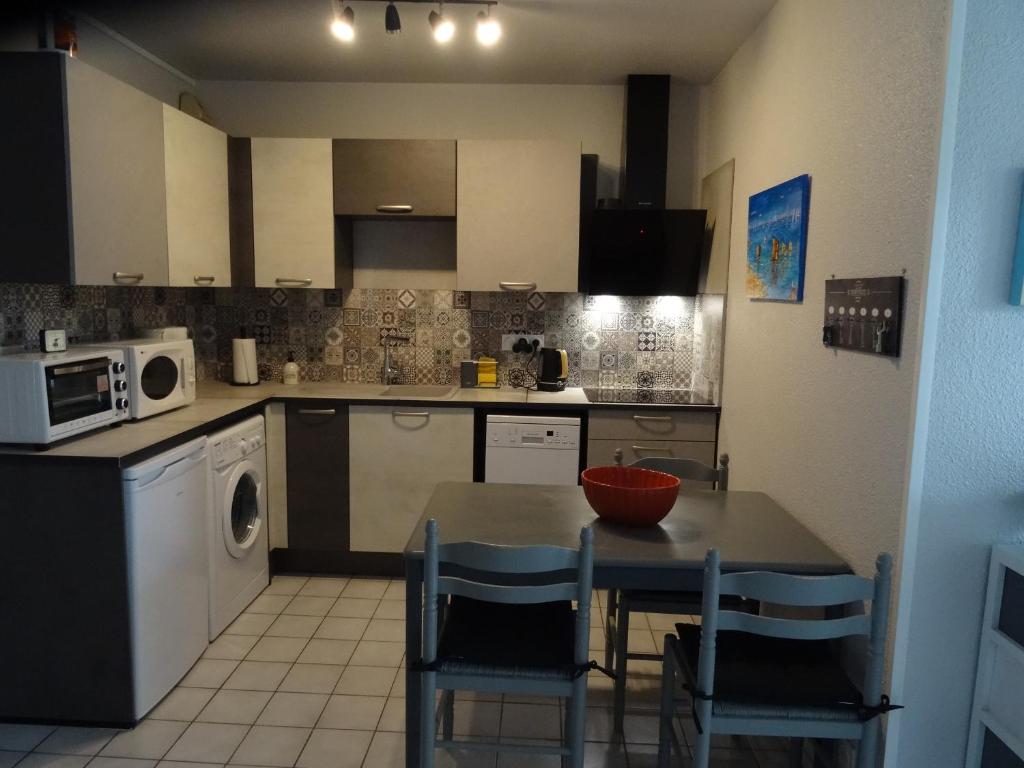 une cuisine avec une table et des chaises et un micro-ondes dans l'établissement Appartement Saint Georges De Didonne, à Saint-Georges-de-Didonne
