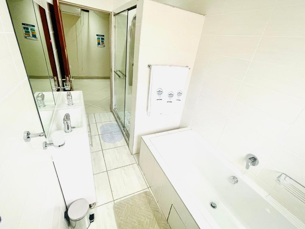 a white bathroom with a shower and a sink at C&C HOTEL VIBES Randpark Ridge JHB 14 Units Available in Boskruin