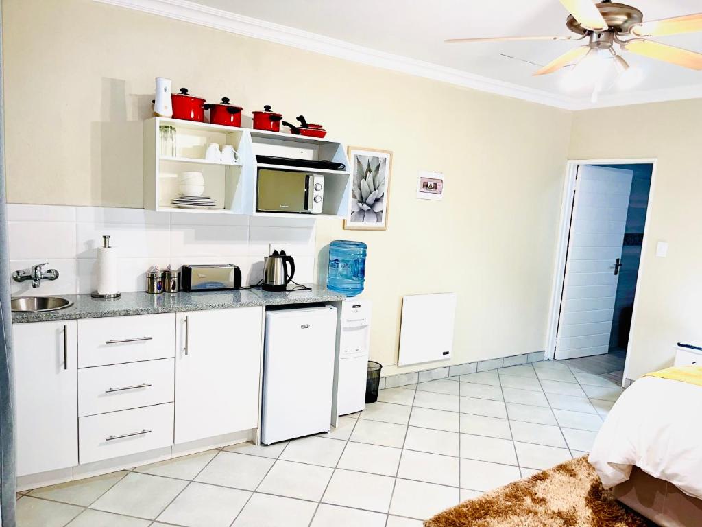 a kitchen with white cabinets and a ceiling fan at C&C HOTEL VIBES Randpark Ridge JHB 14 Units Available in Boskruin