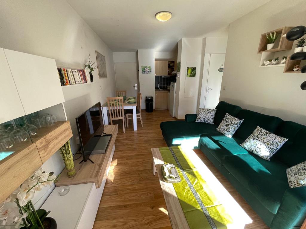 un soggiorno con divano verde e tavolo di JARDINS DE RAMEL – APPT 2106*** - CURE/SKI WIFI a Luchon