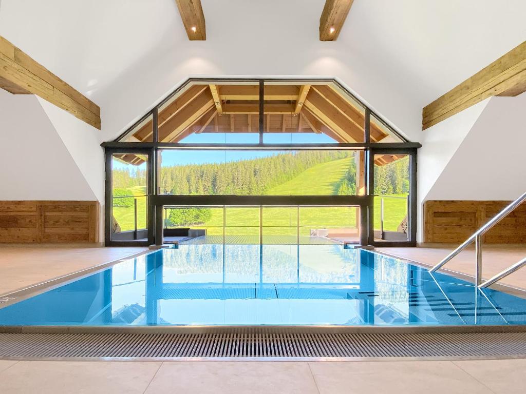 an indoor swimming pool with a large window at SCHWARZENBACH - Apartments & Rooftop Pool in Feldberg