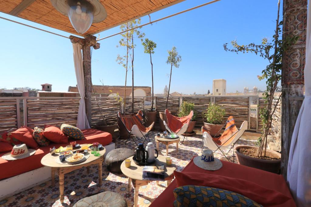 a patio with couches and tables on a balcony at Riad-Shakho-Marrakech in Marrakesh