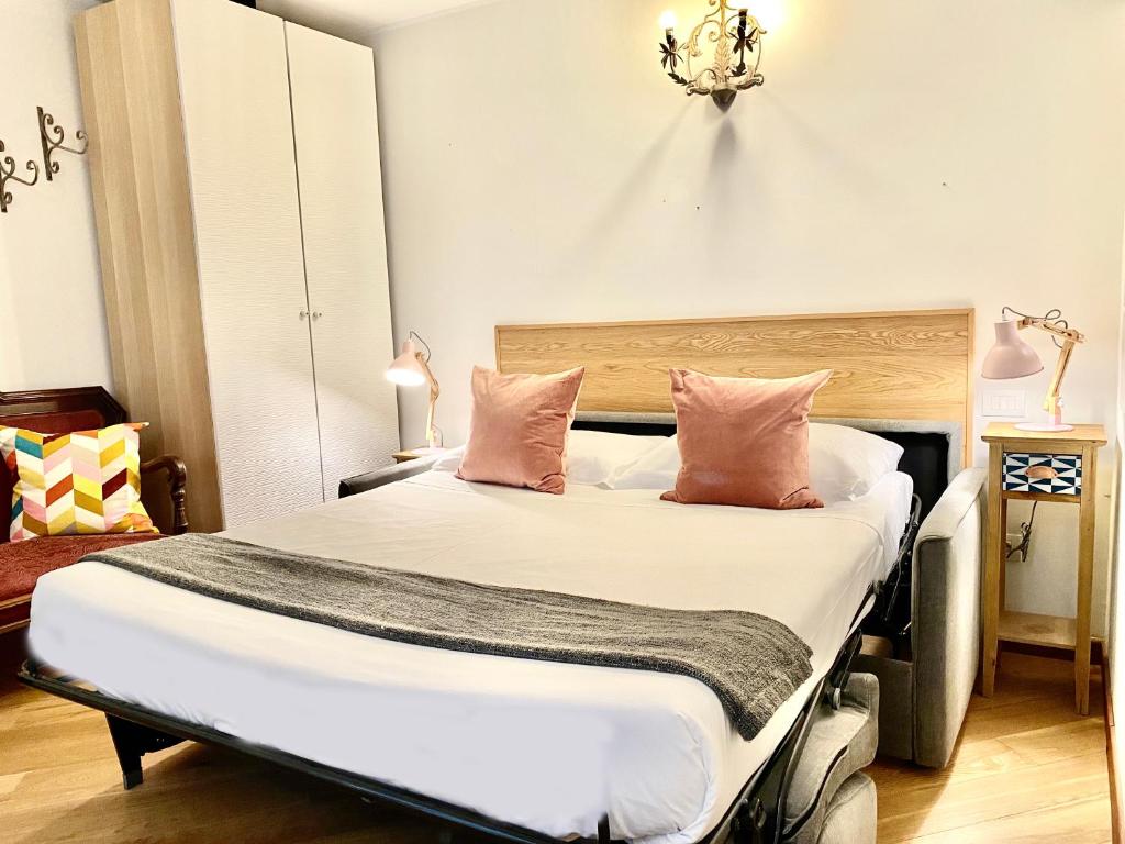 Schlafzimmer mit einem Bett mit weißer Bettwäsche und rosa Kissen in der Unterkunft Palazzina C in Genua