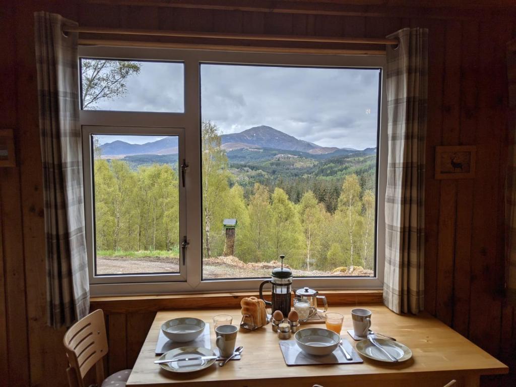 a table in a room with a large window at Faichemard Farm Chalets in Invergarry