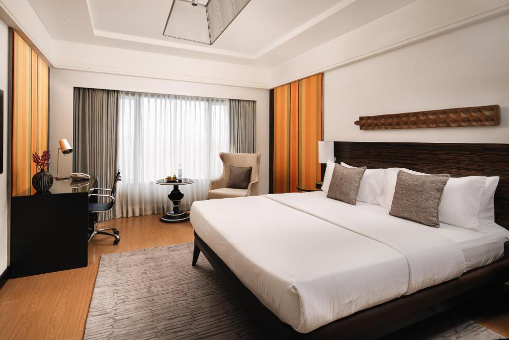 a bedroom with a large white bed and a chair at The Raintree, St. Mary’s Road in Chennai