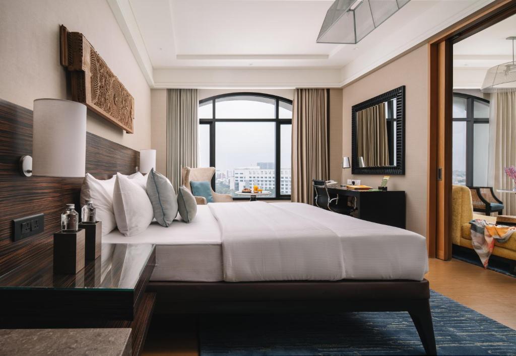 a bedroom with a large bed and a large window at The Raintree, St. Mary’s Road in Chennai