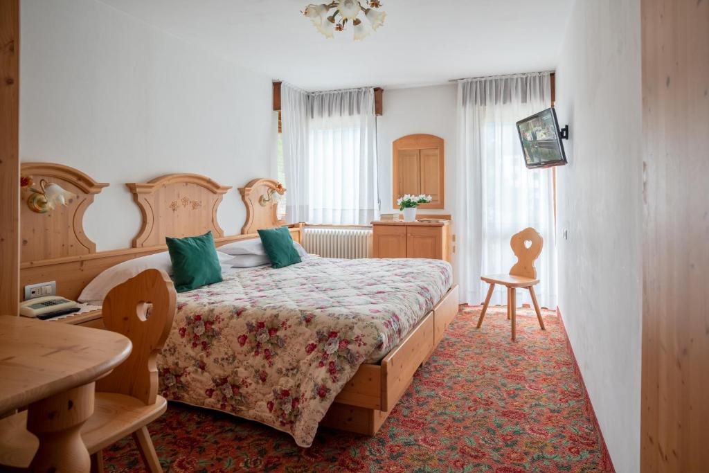 a bedroom with a bed and a table and chairs at Hotel Europa in San Martino di Castrozza