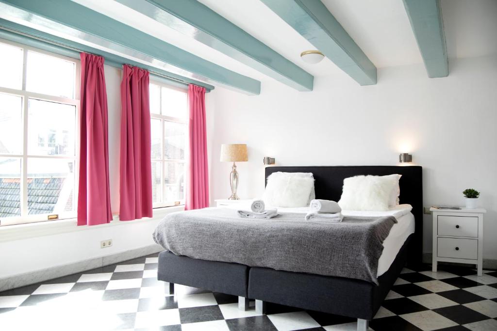 sypialnia z dużym łóżkiem z czerwonymi zasłonami w obiekcie Modern Canal House Loft - City Center w Amsterdamie