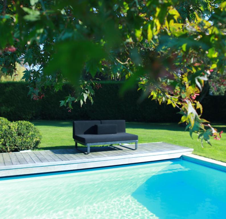 a black couch sitting next to a swimming pool at B&B Josephine in Grimbergen