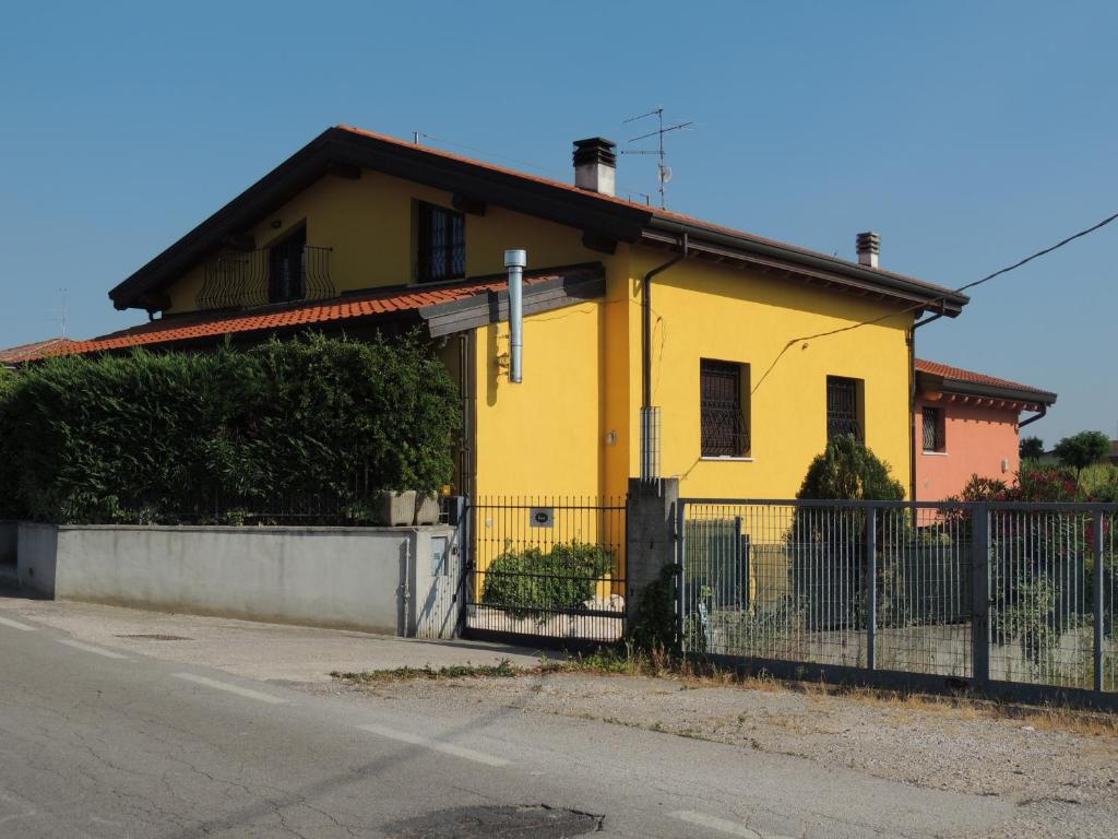a yellow house with a fence in front of it at B&B Renè in Pescantina