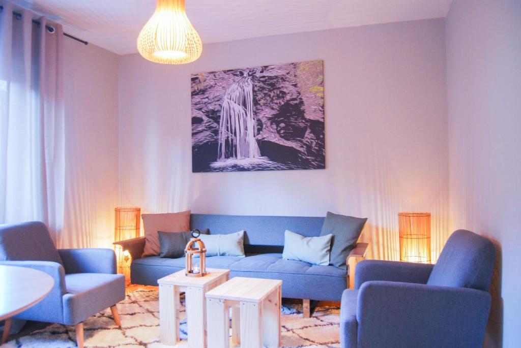 a living room with a blue couch and a waterfall painting at Gästehaus an der Moseltherme in Traben-Trarbach