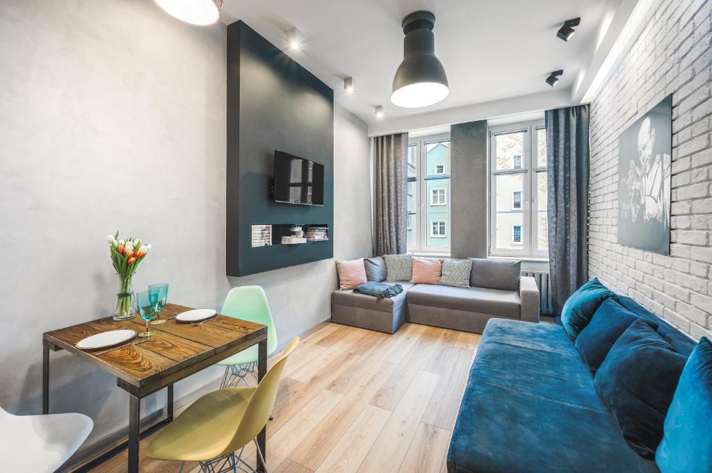 a living room with a blue couch and a table at Apartament Przy Żurawiu in Gdańsk