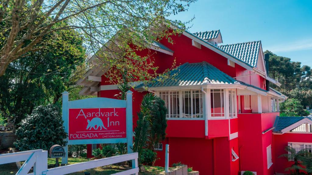 una casa roja con un cartel delante en Aardvark Inn Pousada, en Gramado