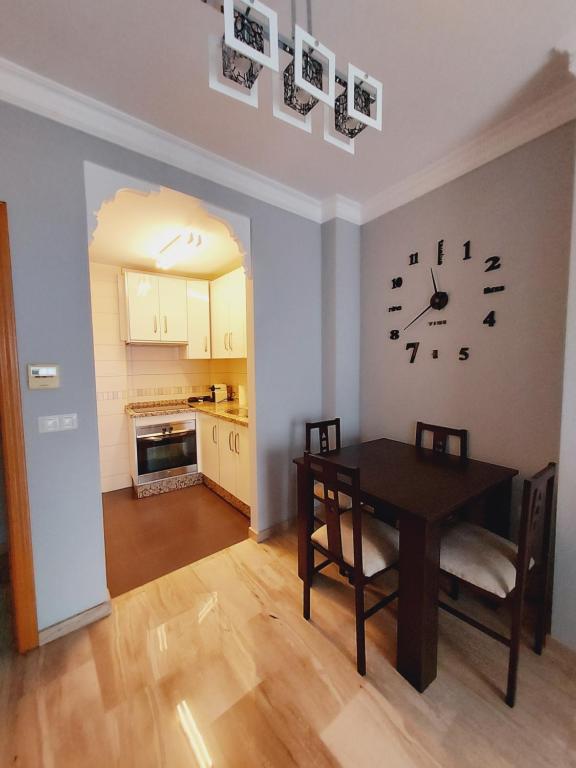a dining room with a table and a clock on the wall at Apartamento La Muralla in Baena