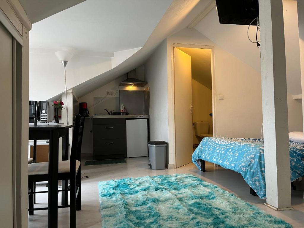 una camera con letto e tavolo e una cucina di Studio-Meublé HyperCentre a Poissy