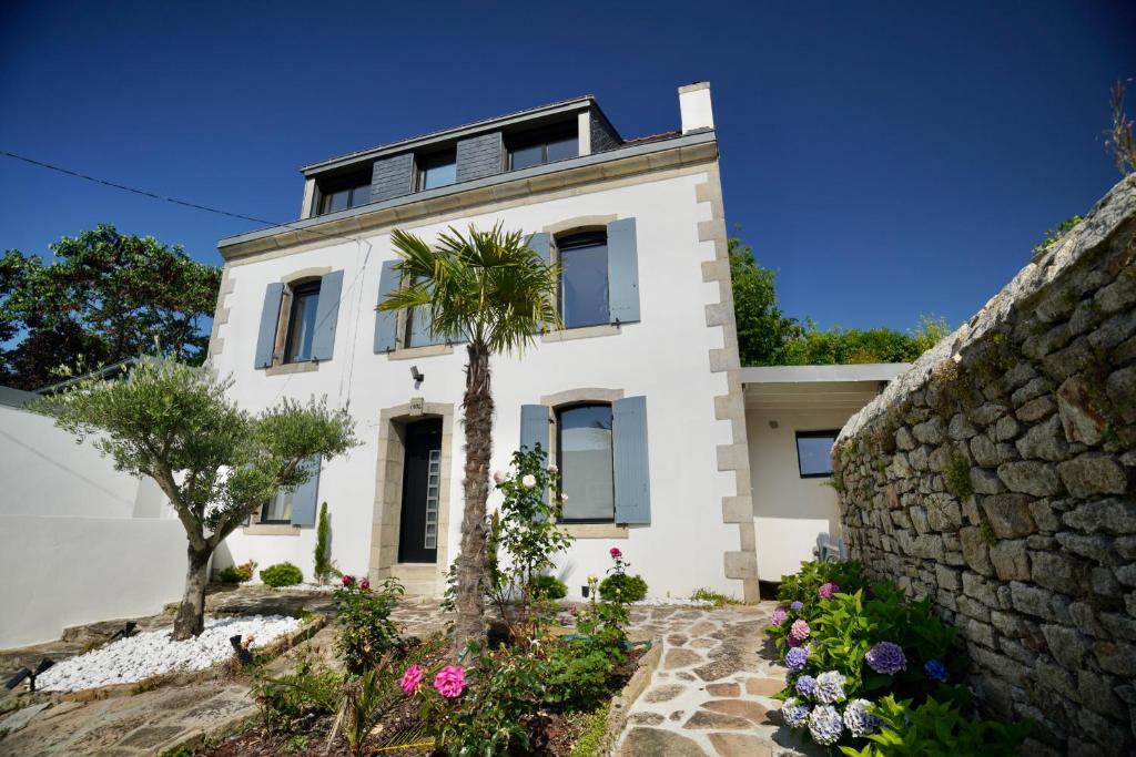 una casa blanca con una palmera frente a una pared de piedra en Maison Haut de Gamme à 5min à pied de la Cathédrale de Quimper, en Quimper