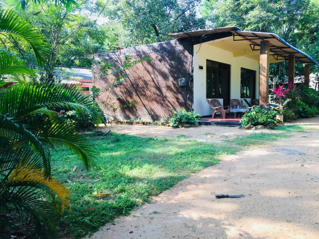 a small house with two chairs in a yard at Gimansa Rest Sigiriya in Sigiriya