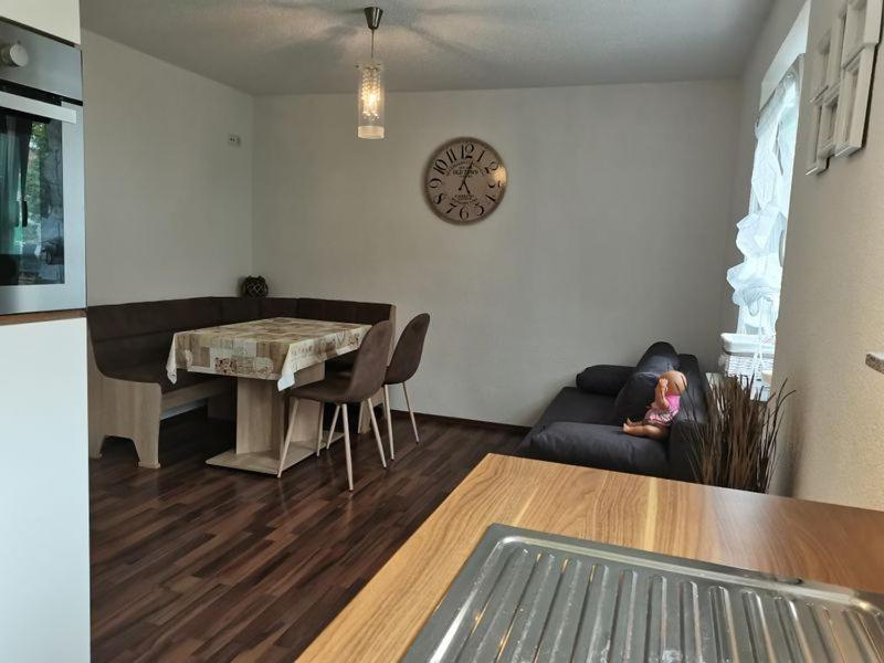 een woonkamer met een tafel, een bank en een klok bij Ferienwohnung Im Drosselnest in Hechingen