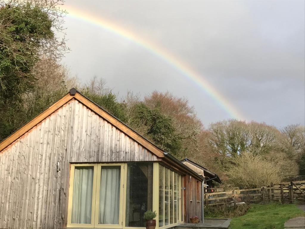 un arco iris en el cielo sobre una casa en Oak Lodge, en Tavistock