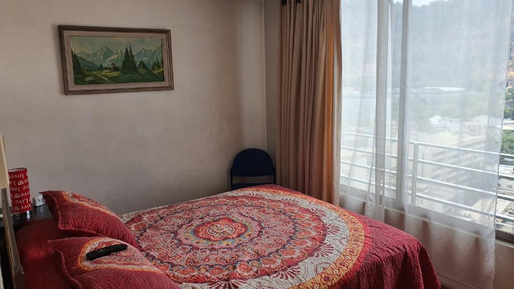 1 dormitorio con 1 cama con manta roja y ventana en Metro Manuel Montt, en Santiago