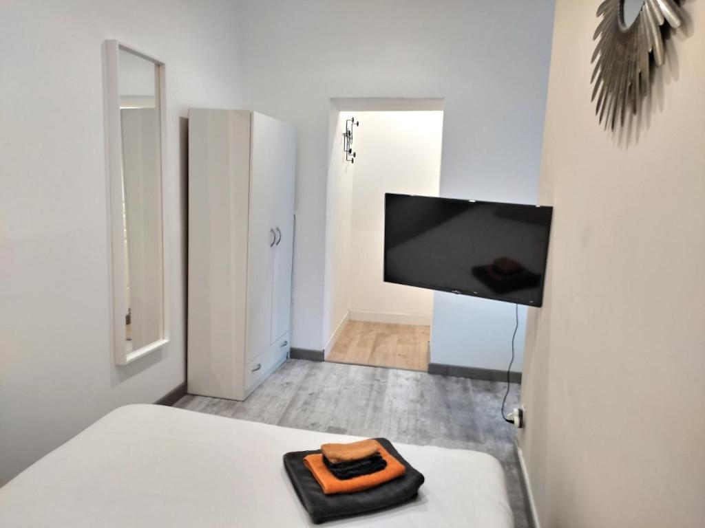 a white room with a bed and a flat screen tv at Chambre 26m - Salon et kitchenette privé - WIFI in Woippy
