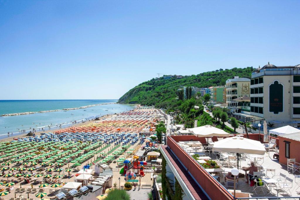 a beach with many umbrellas and crowds of people at Giovanna Regina Hotel in Gabicce Mare