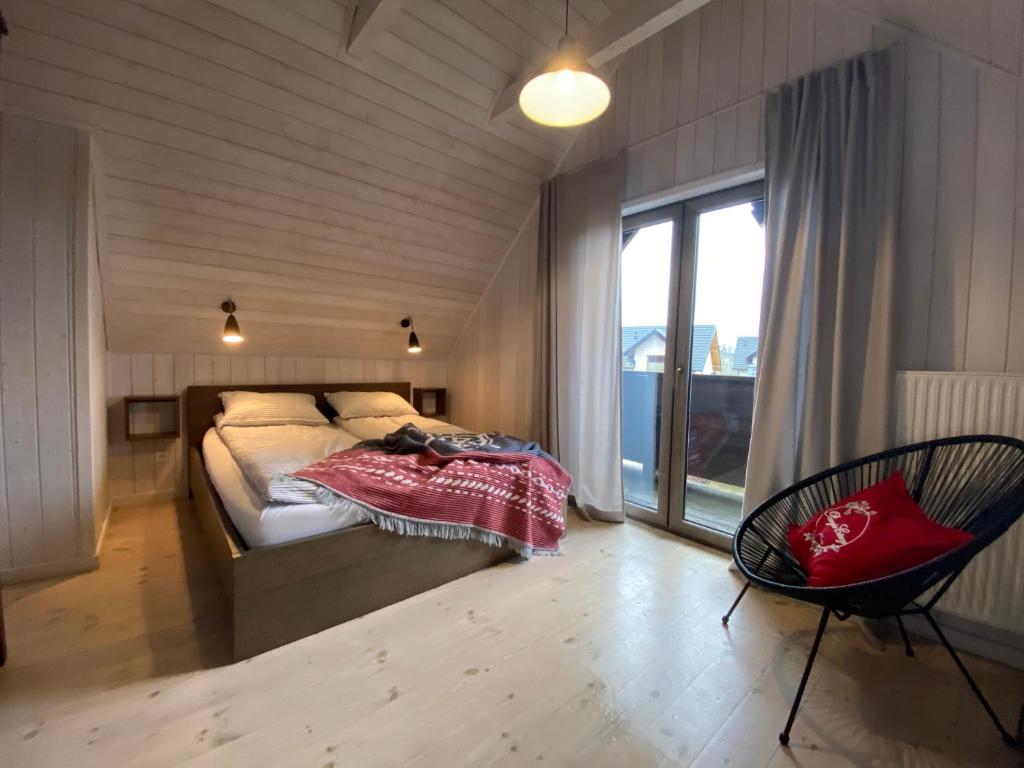 una camera da letto con un letto, una sedia e una finestra di Domki Poezja Ciszy a Dębki