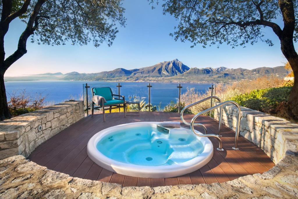 a hot tub on a patio with a view of the water at Villetta Blue Panorama With Jacuzzi in Torri del Benaco