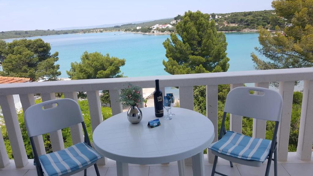 une table et des chaises blanches sur un balcon avec vue sur l'eau dans l'établissement Apartments San, à Lovište