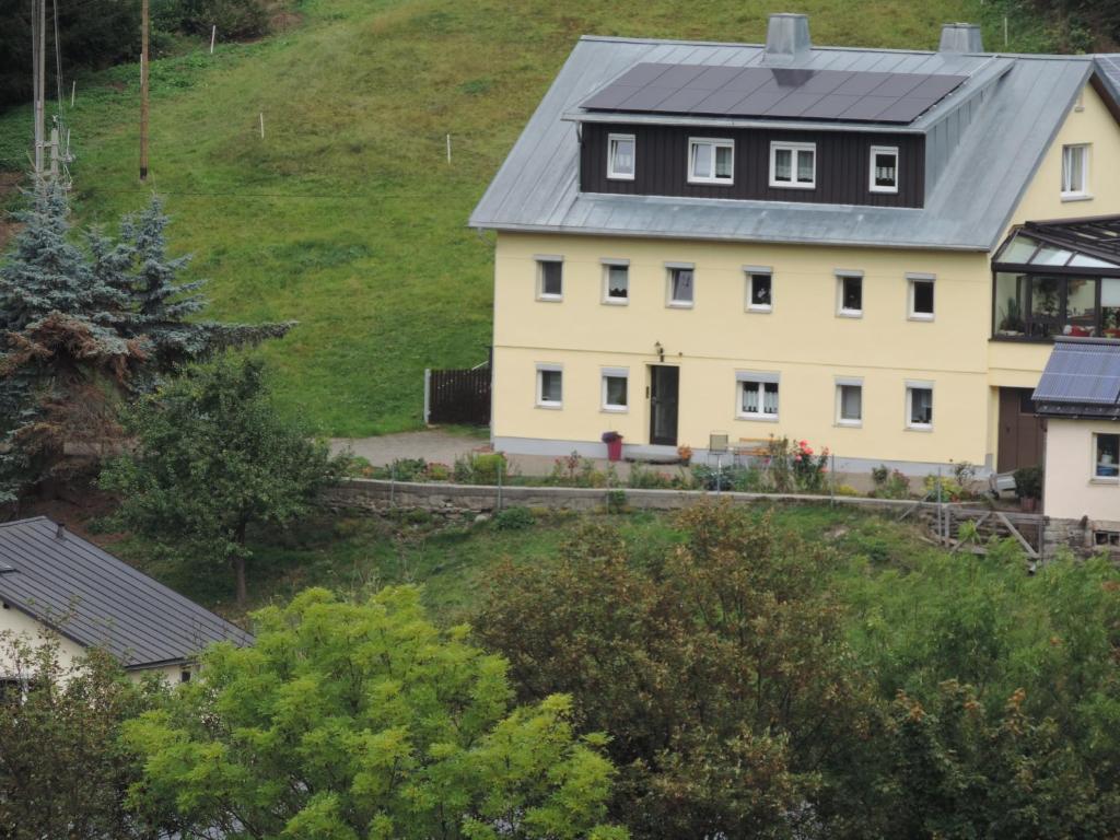a white house with a gray roof on a hill at Sonnenblick Rittersgrün I in Breitenbrunn