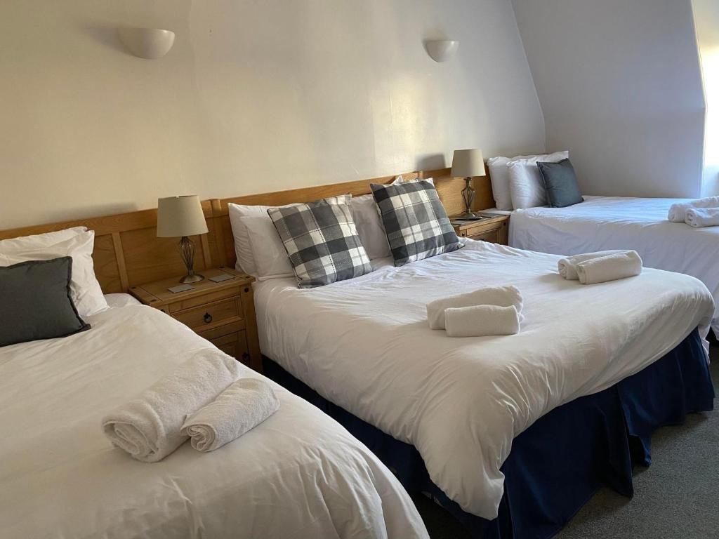 a bedroom with three beds with towels on them at The Black Swan Hotel in Kelso