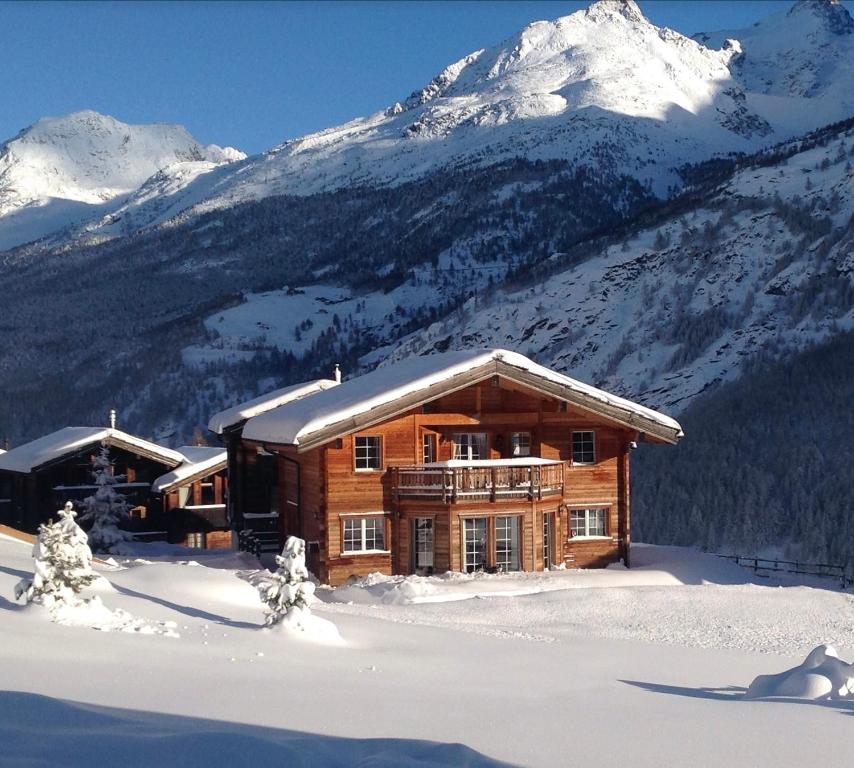 a log cabin in the snow with a snow covered mountain at Chalet Inge in Saas-Fee