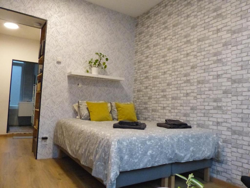 Cette chambre comprend un lit avec des oreillers jaunes et un mur en briques. dans l'établissement Superbe Studio au 1er étage, proche de la gare du Midi, à Bruxelles