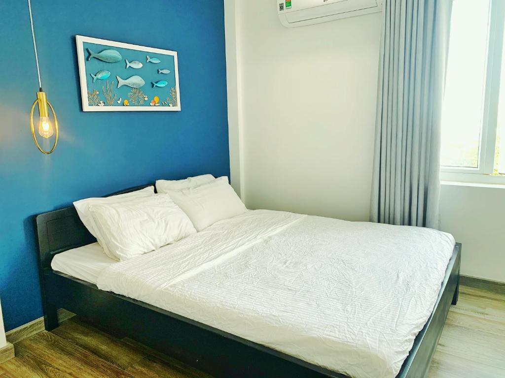 a bed in a room with a blue wall at Room in Vung Tau- Blue Fish Deluxe Room- Phòng Bãi Sau Vũng Tàu in Vung Tau