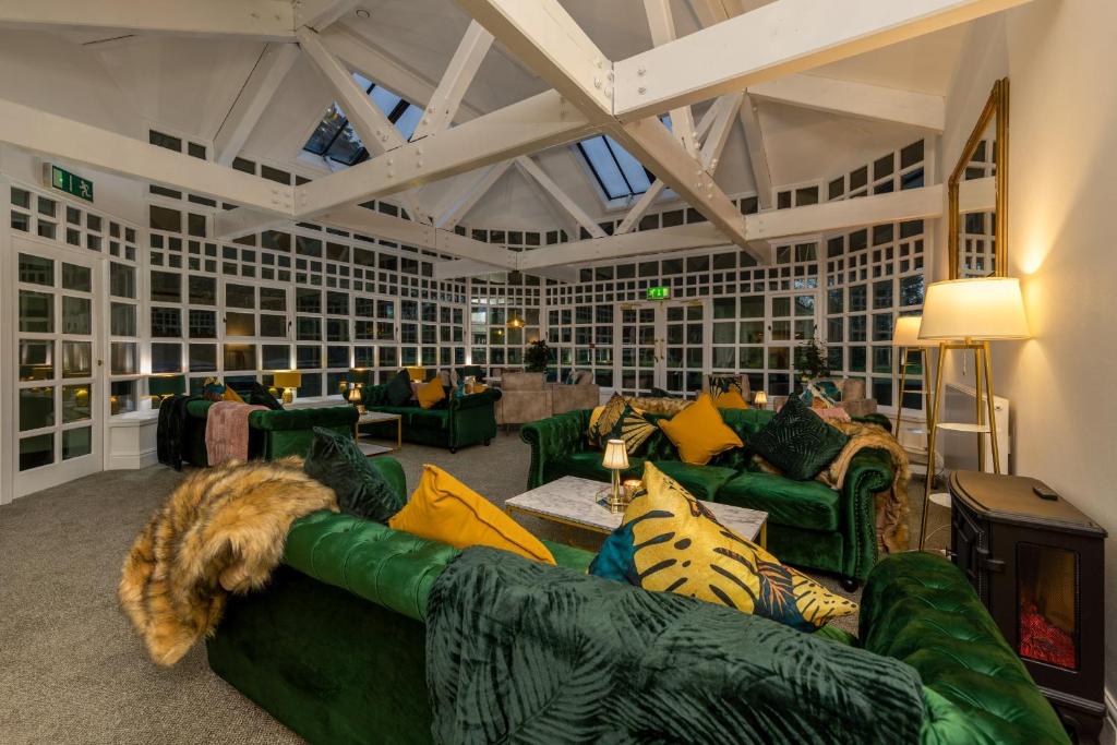 a living room with green couches and a dog laying on a couch at Sella Park Country House Hotel in Seascale