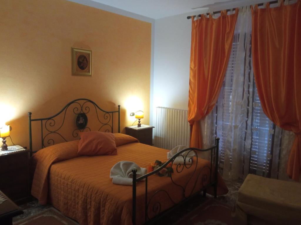 1 dormitorio con 1 cama con sábanas y cortinas de color naranja en Residenza di campagna, en Asís
