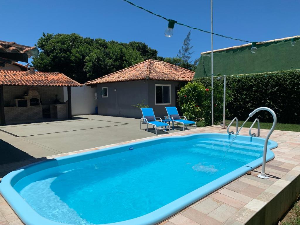 a swimming pool with two chairs and a house at Kitchenette near the Beach/including Breakfast in Búzios