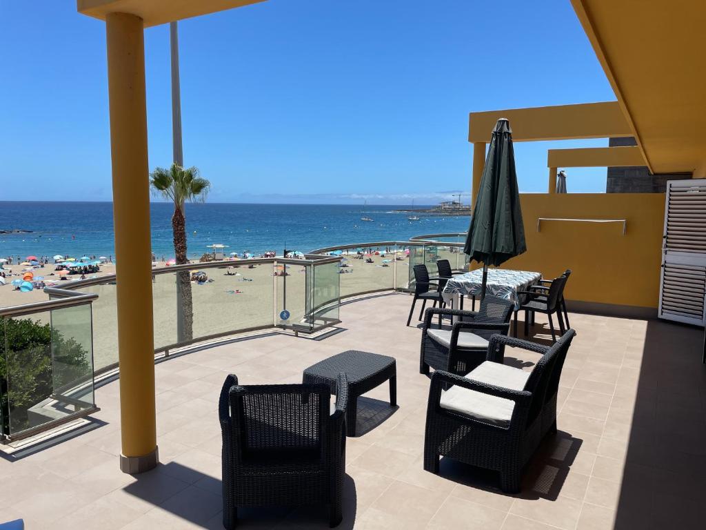 een patio met een tafel en stoelen en het strand bij RentOnTheBeach in Los Cristianos