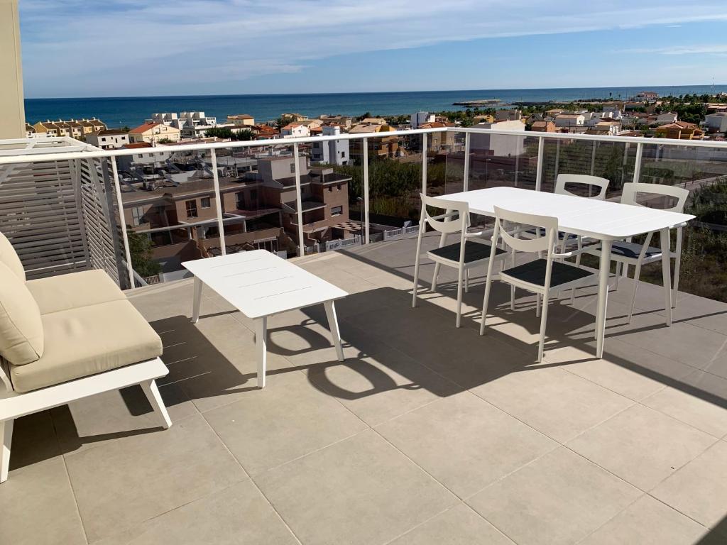 a balcony with white tables and chairs and the ocean at Penthouse panoramic sea view in Oliva