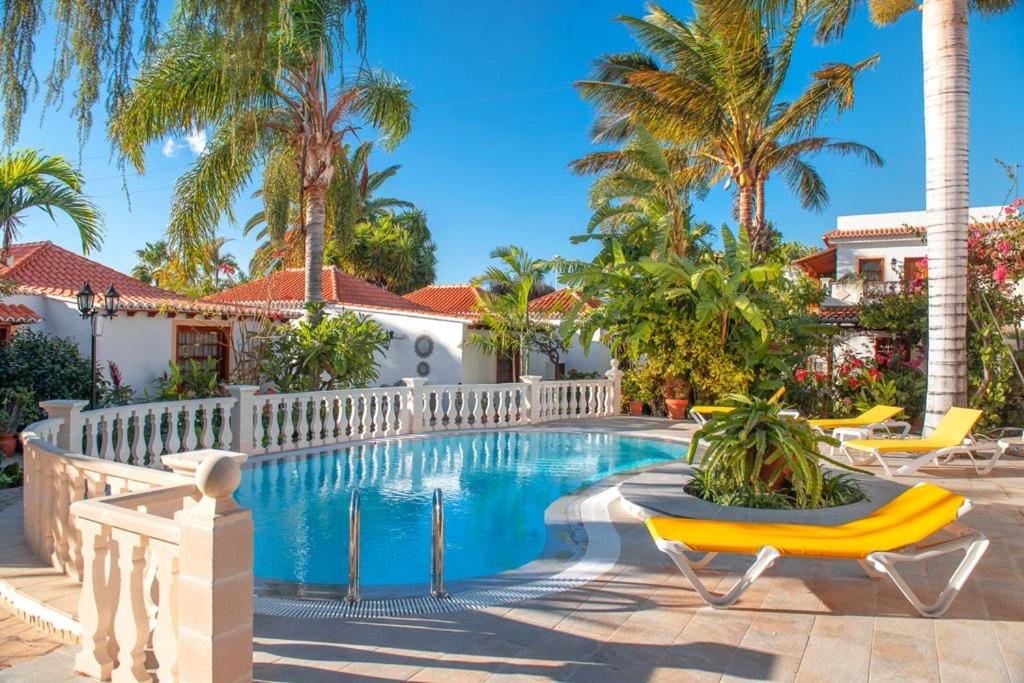 una piscina con sillas y palmeras en Villa Mary, en Tazacorte